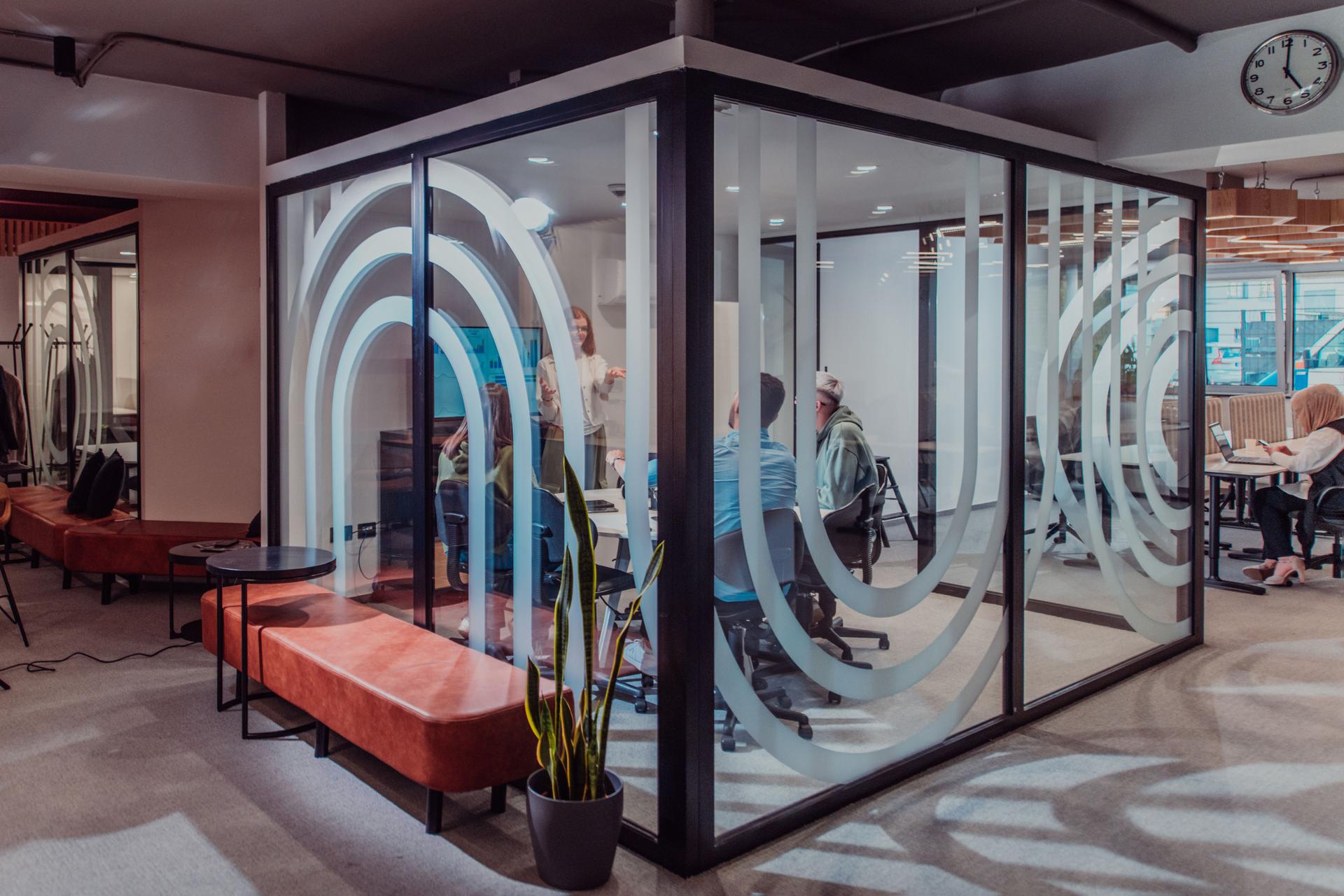 A group of young business entrepreneurs engages in a focused meeting, discussing various business strategies and collaboratively solving challenging problems, showcasing ambition, creativity, and teamwork in modern glass office